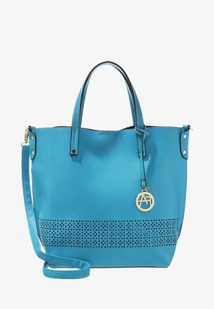 Niebieska skórzana torba typu tote z perforowanym wzorem u podstawy, dwoma uchwytami, odpinanym paskiem na ramię oraz okrągłą złotą zawieszką z logo.