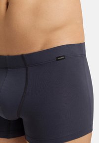 Boxerky z námořnického strečového materiálu s hladkým povrchem, vybavené štítkem s logem na pasu a kontrastním šitím.