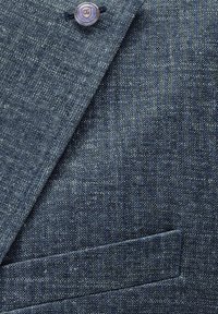 Navy blue textured suit fabric with a subtle pattern, featuring a circular button and a single pocket on the left side.