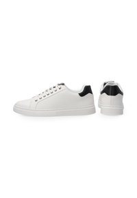 Białe sneakersy wykonane z siateczki i materiałów syntetycznych z czarnym akcentem na pięcie. Posiadają płaską podeszwę i sześć otworów na sznurówki.