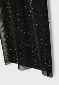 Przezroczysty czarny materiał o gładkiej teksturze zdobiony małymi, odblaskowymi srebrnymi kropkami, tworzącymi kropkowany wzór na powierzchni.