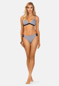 Czarnobiały kostium bikini w kratkę, składający się z biustonosza w kształcie V z regulowanymi ramiączkami oraz pasujących majtek w wysokim stanie z czarnymi akcentami.