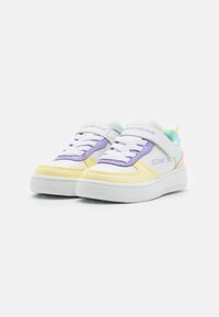 Sapatilhas brancas com detalhes em roxo, amarelo e menta; tiras de fecho por pressão, colarinho acolchoado e sola de borracha texturizada para aderência.
