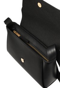 Fekete bőr kézitáska hajtókával és arany mágneses záróelemmel, a nyitott belső tér egy arany cipzáros rekesszel.