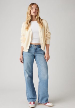 Off-white ribbed cardigan, valkoinen istuva crop-top, vaaleansiniset leveälahkeiset farkut ja valkoiset tennarit punaisilla raidoilla. Yksinkertainen muotoilu ja rento Istuvuus.