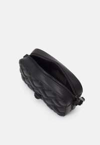 Borsa in pelle nera trapuntata con chiusura a zip e motivo testurizzato. Caratterizzata da un'impugnatura rotonda e un interno foderato. Forma rettangolare compatta.