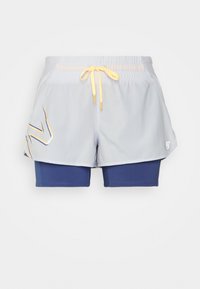 Ljust grå träningsshorts med gul dragsko och blåa innerbyxor med åtsittande passform, med en stiliserad logotyp på det vänstra ytterlagret.