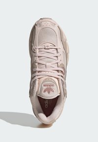 Svijetlo ružičasti tenisici s mrežastim i sintetičkim gornjištem, okruglim vrhom, ravnim vezicama, podstavljenim ovratnikom i teksturiranim potplatima. Adidasov logo na jeziku.