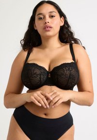 Svart spets-bh med underwire, blommönster, mitt-båge-detalj och justerbara axelband. Matcher med högmidjade svarta trosor.