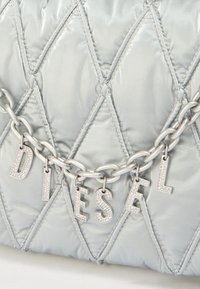 Ασημένια τσάντα με επένδυση και υφή ραμμένη σε σχήμα ρόμβων, με ασημένια αλυσίδα που φέρει γράμματα από στρας που σχηματίζουν το "DIESEL". Λείο, γυαλιστερό υλικό.