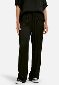 Pantalones de sat�én negros con un corte holgado, que cuentan con una cinturilla elástica, bolsillos laterales y una textura suave y brillante.