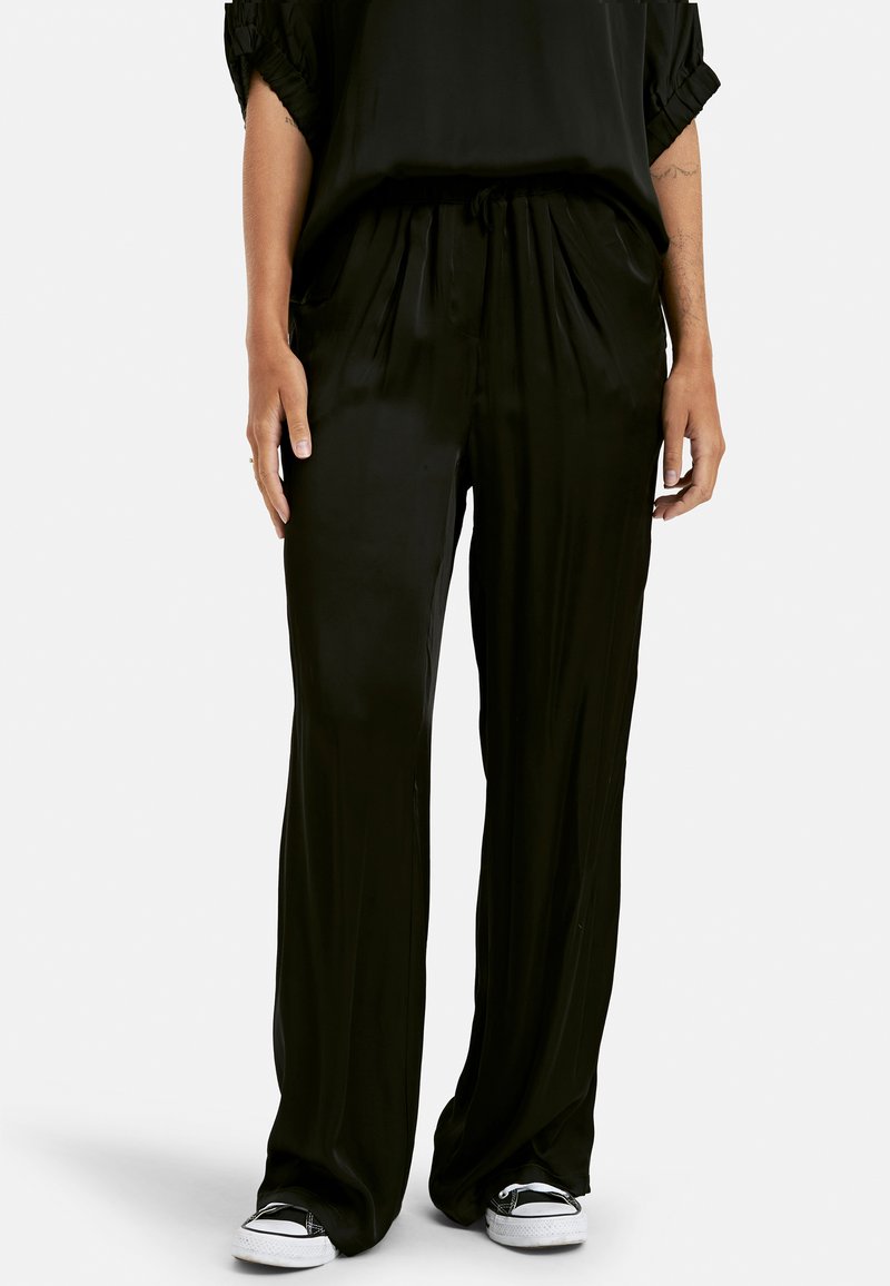 Pantalones de satén negros con un corte holgado, que cuentan con una cinturilla elástica, bolsillos laterales y una textura suave y brillante.