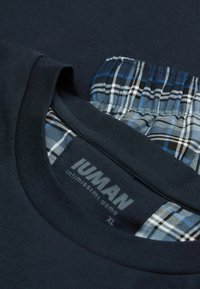 Marineblaue T-Shirt mit Rundhalsausschnitt, unter dem Kragen aus einem blau-weißen Karostoff und einem aufgedruckten Etikett mit der Aufschrift "IUMAN XL."