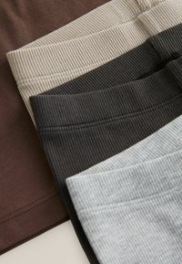 Four pairs of ribbed waistbands in brown, beige, dark gray, and light blue, featuring distinct textures and neutral color tones.