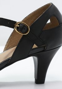 Chaussure à talon haut en cuir noir avec une finition texturée, munie d'une boucle dorée, de côtés ouverts et d'un talon robuste et profilé.