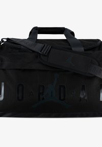 Bolso de viaje negro con un material sintético texturizado, que presenta un destacado logo de Jordan y el nombre de la marca, cierre de cremallera y correa de hombro desmontable.