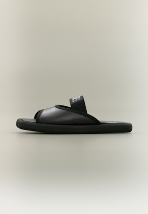 Black slide sandal with thick sole and wide strap featuring white printed text, shown in side profile on neutral background.