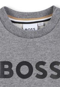 Szara bluza z okrągłym dekoltem i czarnym logo "BOSS". Posiada miękką fakturę i paskowany detal wewnątrz kołnierza.