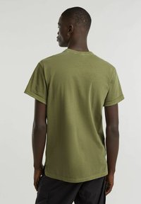 T-shirt in cotone verde oliva con maniche corte, scollatura rotonda e vestibilità comoda. Design semplice senza motivi o dettagli visibili.