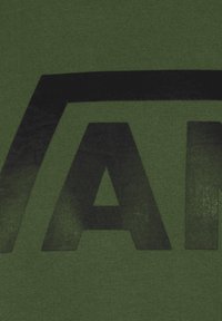 Tecido verde oliva con una gran impresión mate negra de la palabra "VANS". La textura es suave con un ligero brillo en el área impresa.