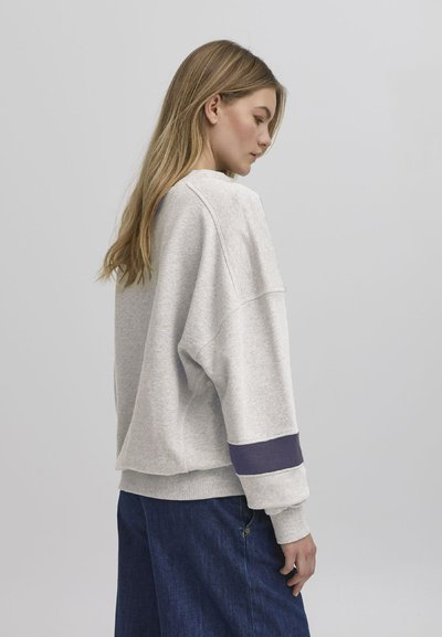 Grå sweatshirt med senket skuldre og marineblå aksentstripe på mansjetten. Myk stoff, avslappet passform og rund hals. Kombinert med denim.