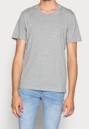 Gray cotton V-neck t-shirt with short sleeves. Straight cut with a soft texture. Worn with light blue jeans. Minimal branding detail visible.