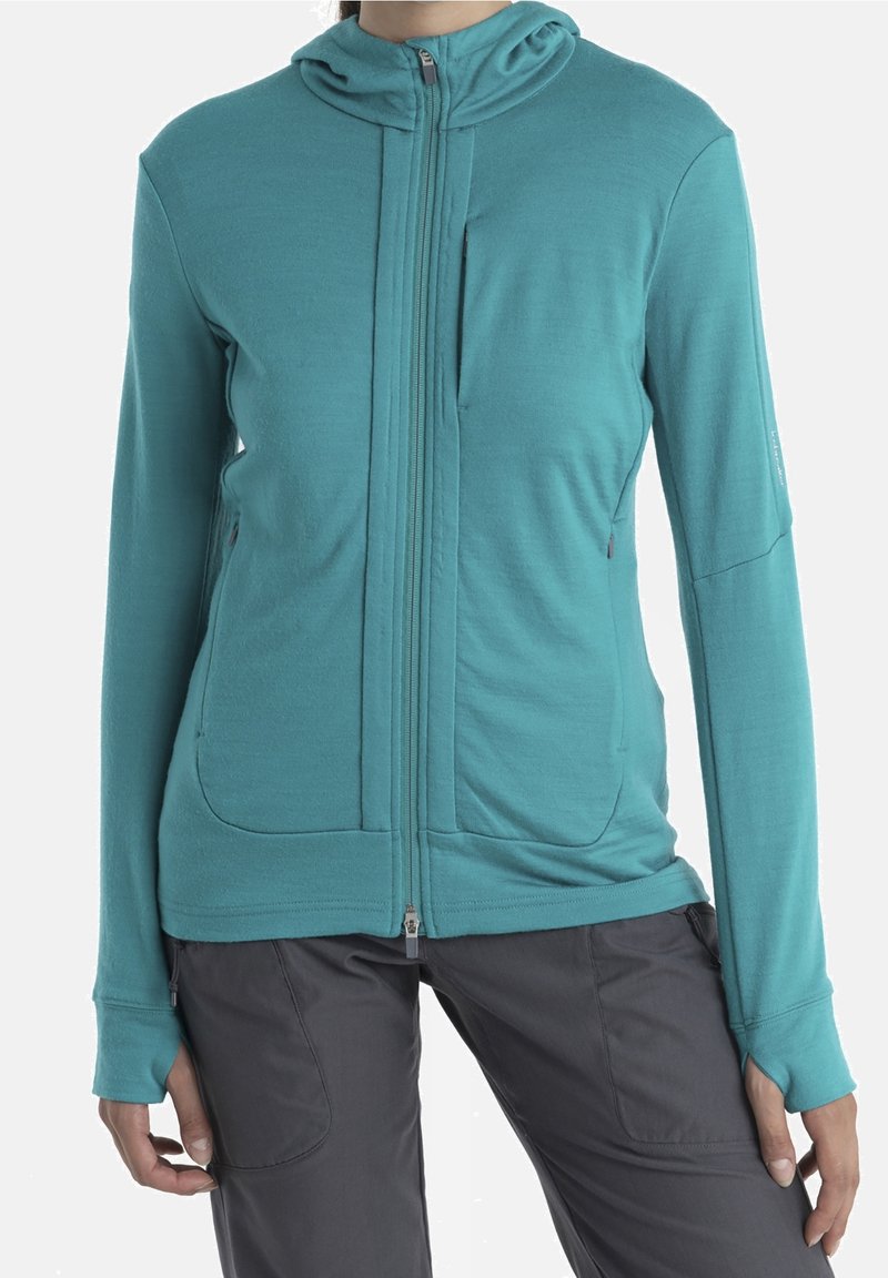 Felpa zip-up color teal realizzata in tessuto morbido, con zip frontale, tasche a marsupio e cappuccio integrato; texture liscia, stile aderente.