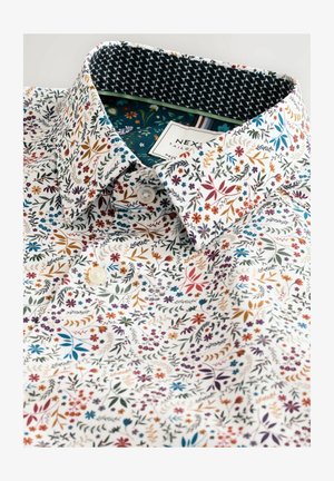 Weißes Hemd mit floralem Muster und mehrfarbigen Blumen. Mit Kragen, der ein kontrastierendes, gemustertes Innenkragen hat. Knopfverschluss vorne.