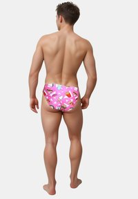 Drengs svømmebukser i pink stof med et mønster af madikoner, herunder is og pizza, med en tætsiddende pasform og glat tekstur.