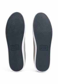 Sneaker Tommy Hilfiger con tomaia grigia, suola intermedia bianca e suola esterna texture blu navy con dettaglio del logo.
