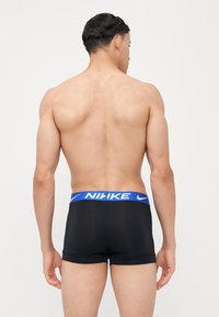 Zwarte boxershorts met een blauwe tailleband met het "NIKE" logo. De stof is glad, met een aansluitend ontwerp en een naadloze achterkant en korte pijpen.