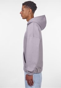 Hellgrauer Kapuzenpullover mit Kängurutasche, gerippten Bündchen und Saum, aus weichem, strukturiertem Stoff gefertigt.