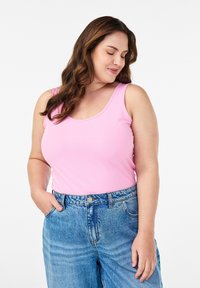 Vaaleanpunainen hihaton paita, jossa on pyöreä kaula-aukko, yhdistetty korkeavyötäröisiin sinisiin farkkushortseihin. Liukas kangas, rento malli ja ei näkyviä kuvioita.