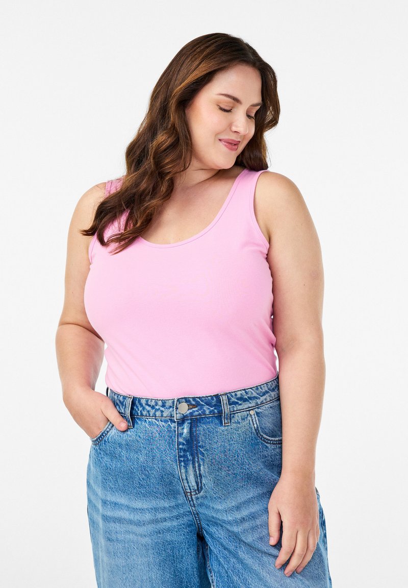 Vaaleanpunainen hihaton paita, jossa on pyöreä kaula-aukko, yhdistetty korkeavyötäröisiin sinisiin farkkushortseihin. Liukas kangas, rento malli ja ei näkyviä kuvioita.