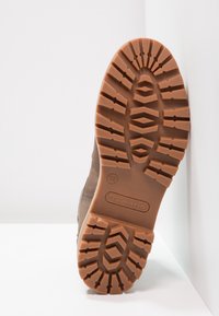 Brauner Gummistiefelsohle mit tiefen Profilmustern, markiert mit "tamaris", Größe 38, zeigt eine strukturierte Oberfläche für verbesserten Grip und Langlebigkeit.
