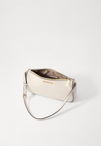 Borsa in pelle color crema con hardware dorato, chiusura zip e tracolla removibile. Presenta una texture liscia e un design minimalista.