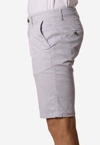 Pantalones cortos hasta la rodilla de color gris claro usados por una persona, que muestran un bolsillo lateral, un bolsillo trasero con botón y una cinturilla con trabillas.