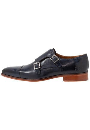Scarpa elegante in pelle nera con doppia fibbia monk, fibbie argento, suola marrone, tacco basso e punta sagomata.