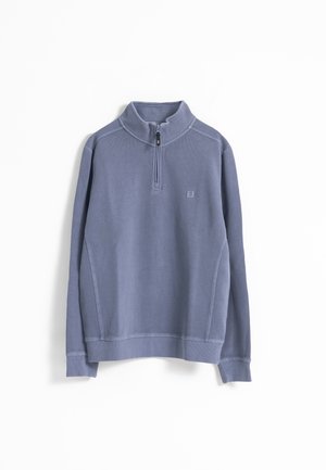 Sudadera de pullover en azul claro con un cuello con cremallera de un cuarto, tejido texturizado y costuras planas. Presenta un pequeño logo en el pecho.