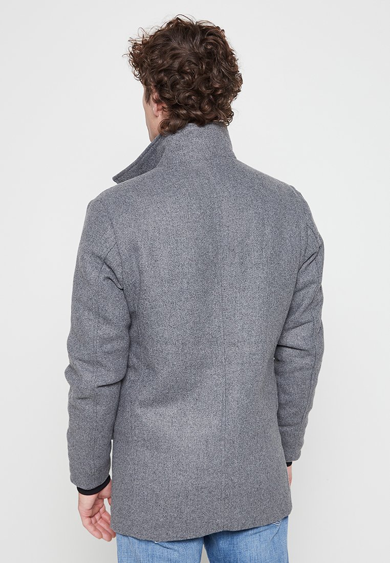 Szary, teksturowany wełniany płaszcz z wysokim kołnierzem, długimi rękawami i prostym krojem. Charakteryzuje się czystymi liniami i minimalnym wzornictwem.