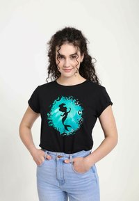 Svart t-shirt med en teal grafisk design av en havsfru-silhuett inuti en virvlande dekorativ ram. Har korta ärmar och en avslappnad passform.