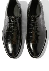 Zapatos oxford negros con acabado brillante en cuero de cocodrilo, con puntera redondeada y diseño de cordones de cinco ojales. Detalle de superficie texturizada.