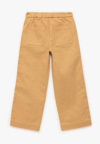 Katoenen broek in een tan kleur met een elastische tailleband, brede benen en twee achterzakken. De stof is glad met een subtiele textuur.