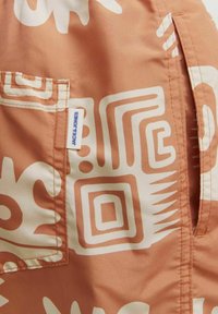 Patroonstof in warm perzik met witte geometrische en abstracte ontwerpen. Heeft een patchzak en een label met "JACK & JONES."