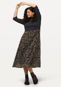 Czarnoszary top z rękawami do trzech ósmych oraz maxi spódnica w kwiatowy wzór w ciemnych odcieniach, z falbanami i botkami na kostkę.