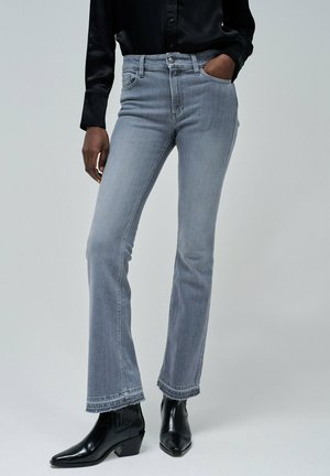 Jeans grises acampanados de mezclilla con un ligero efecto desgastado, que cuentan con un diseño estándar de cinco bolsillos y detalles de dobladillo sin rematar en los puños.