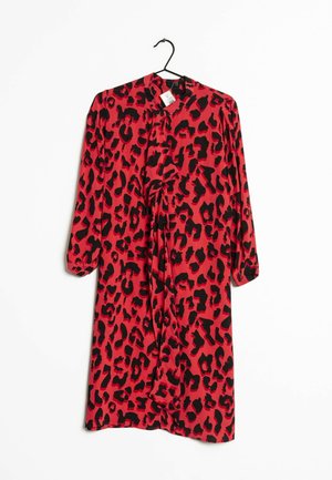 Rode jurk met lange mouwen en zwarte luipaardprint hangt aan een zwarte hanger tegen een witte achtergrond, met een knoopdetail aan de voorkant.
