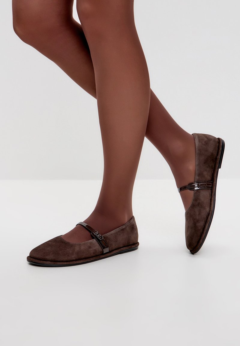 Ballerine in suede marrone con un design elegante, dettaglio della fascia alla caviglia e una texture liscia. Settimana su uno sfondo chiaro, evidenziando la loro forma.