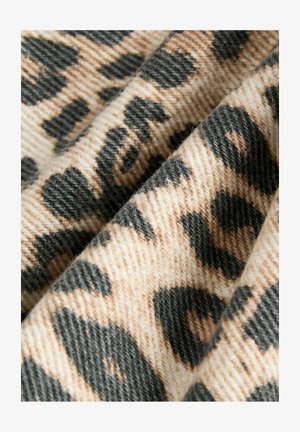 Leopárd mintázatú szövet, texturált felülettel, bézs és fekete színekben, amely közelről mutatja a szőtt részleteket és a mintát.