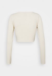 Gekürztes langärmeliges Oberteil aus hellbeigem, geripptem Stoff, mit rundem Ausschnitt und figurbetonter Silhouette. Glatte Textur, minimalistische Details.